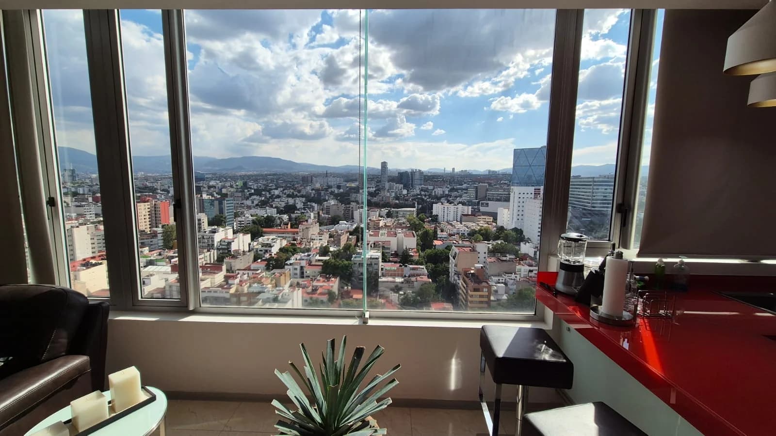 Vista de la ciudad y las montañas desde el ventanal de un departamento.